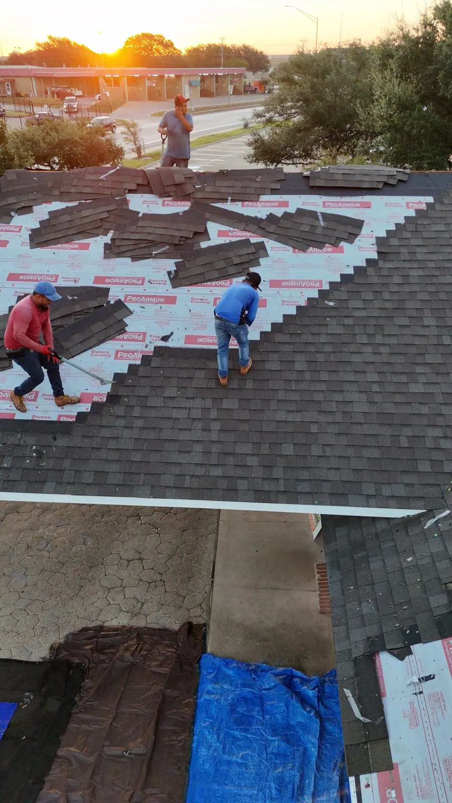 Roofers working a tear off at golden hour on a commercial building